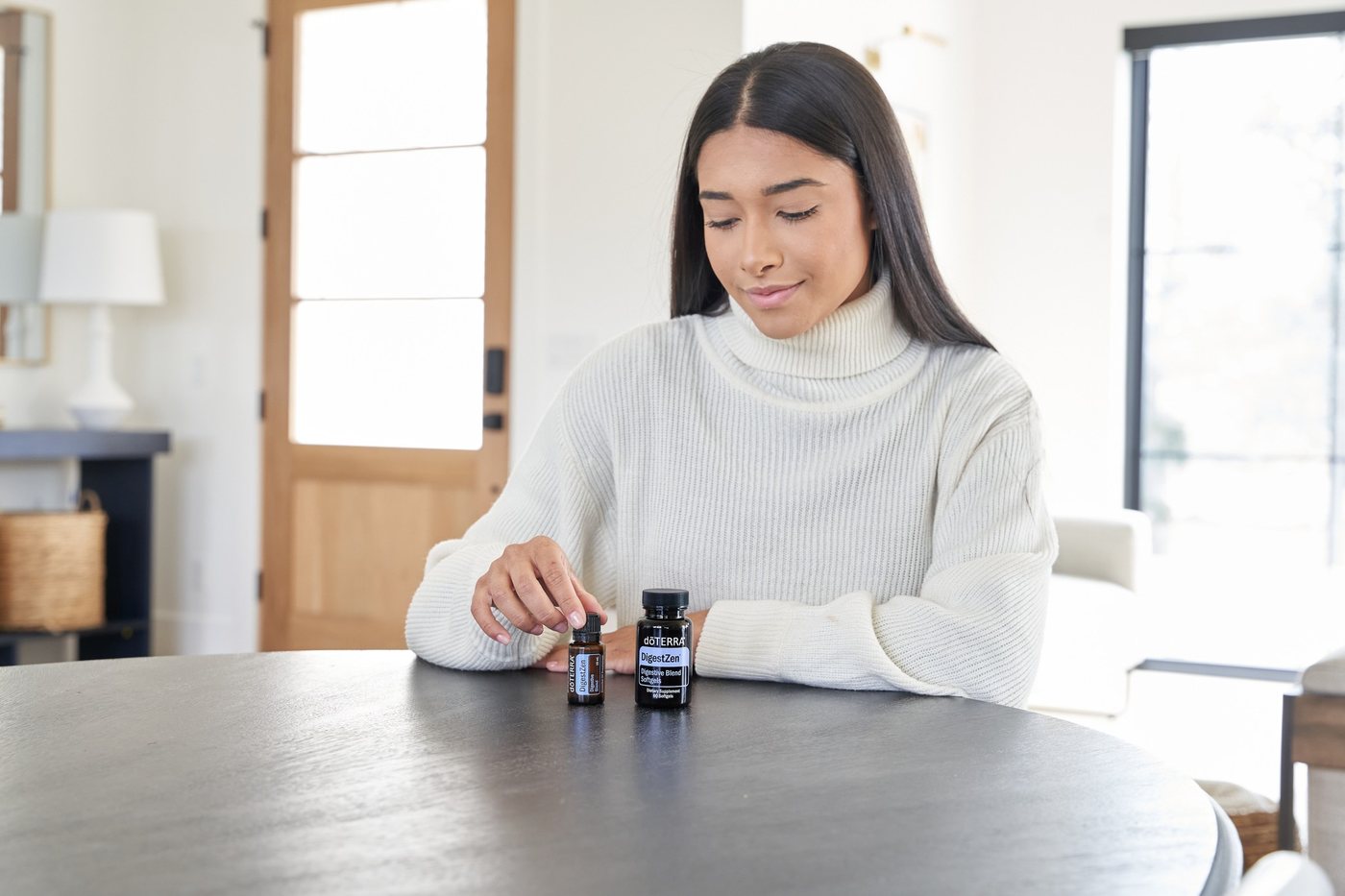 白いセーターの女性がテーブルでオイルのボトル2本を手にしている