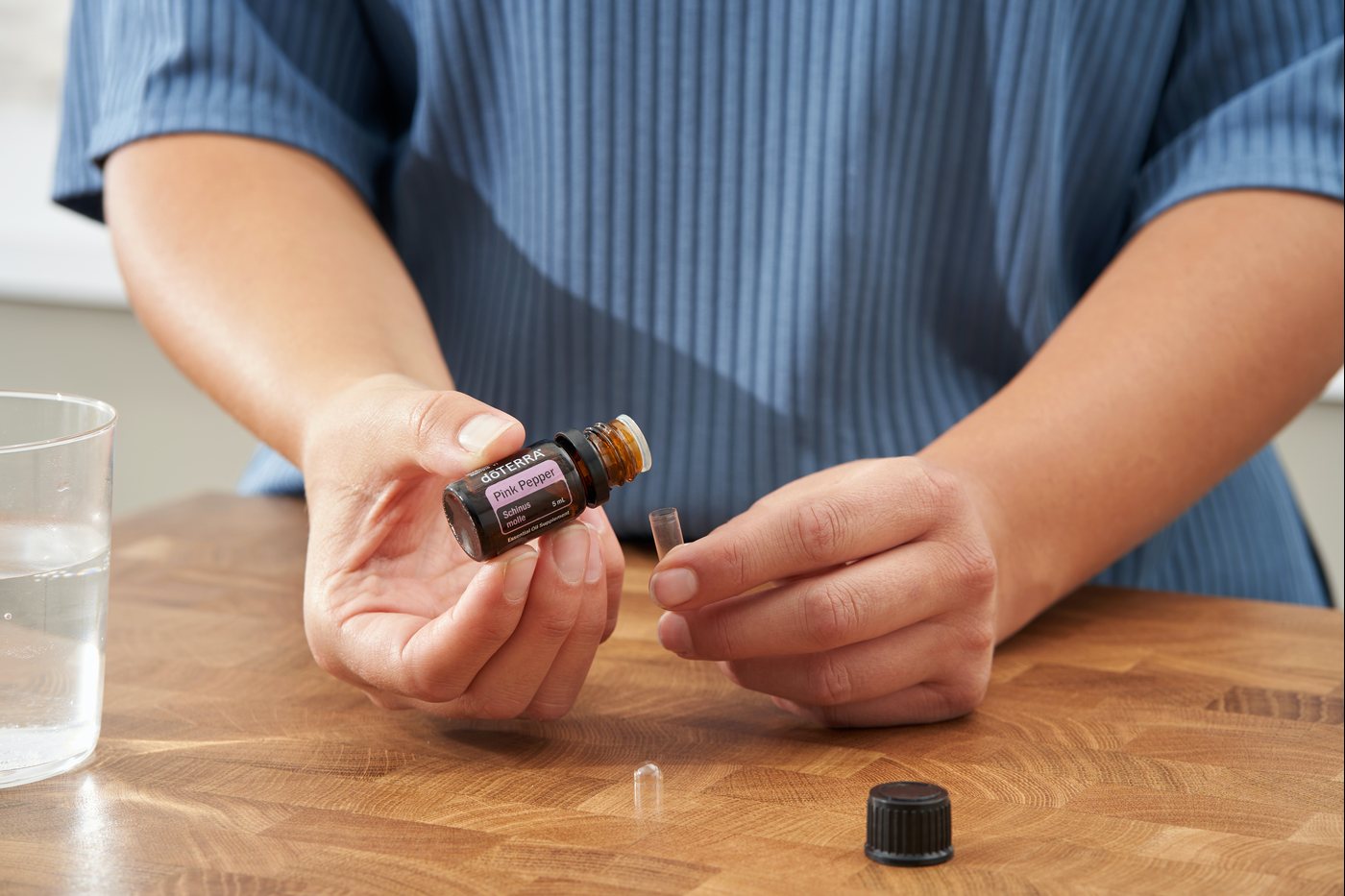 Hands opening a dōTERRA bottle and checking the cap