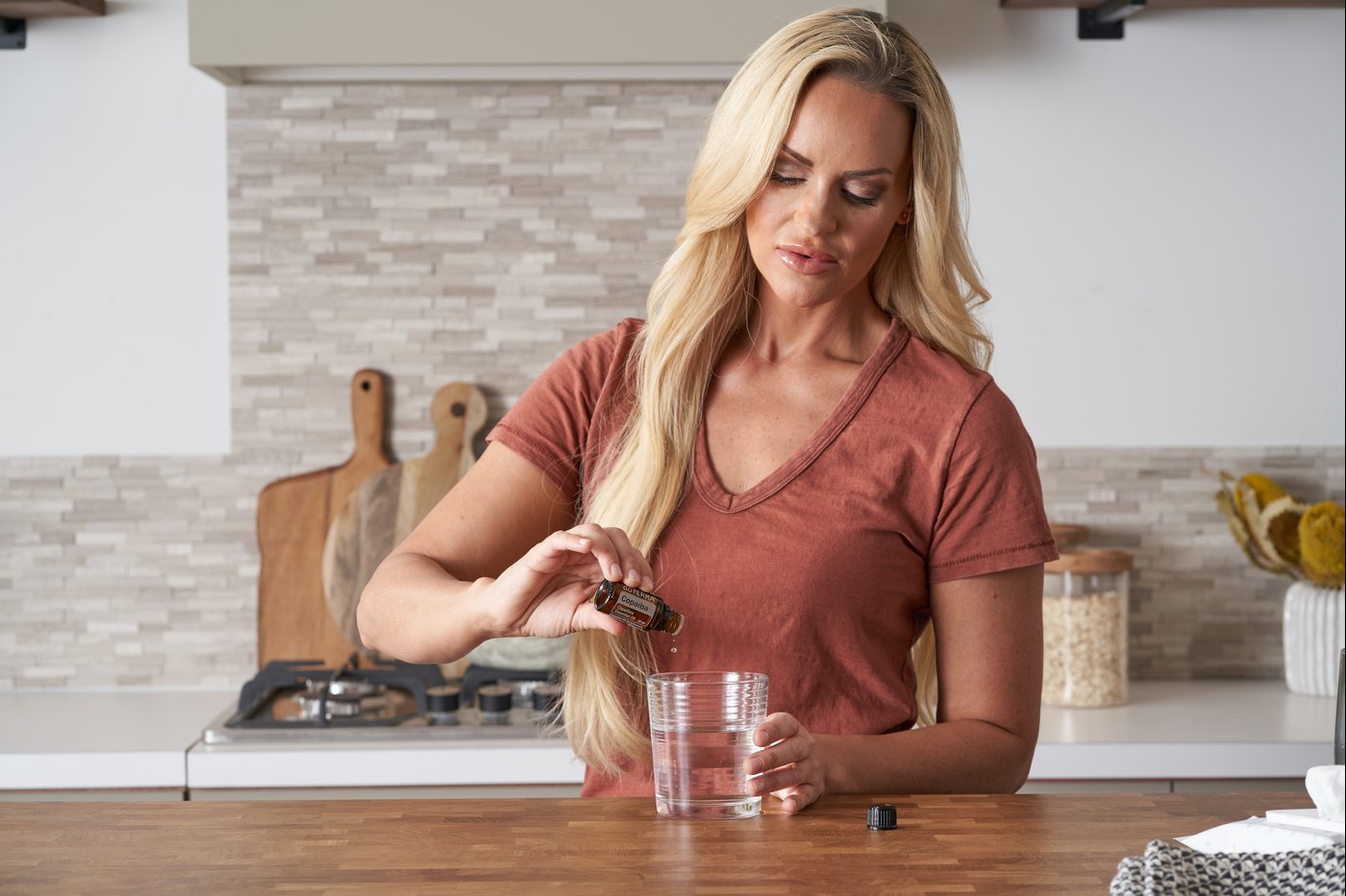Femme ajoutant une goutte d’huile dōTERRA dans un verre en cuisine
