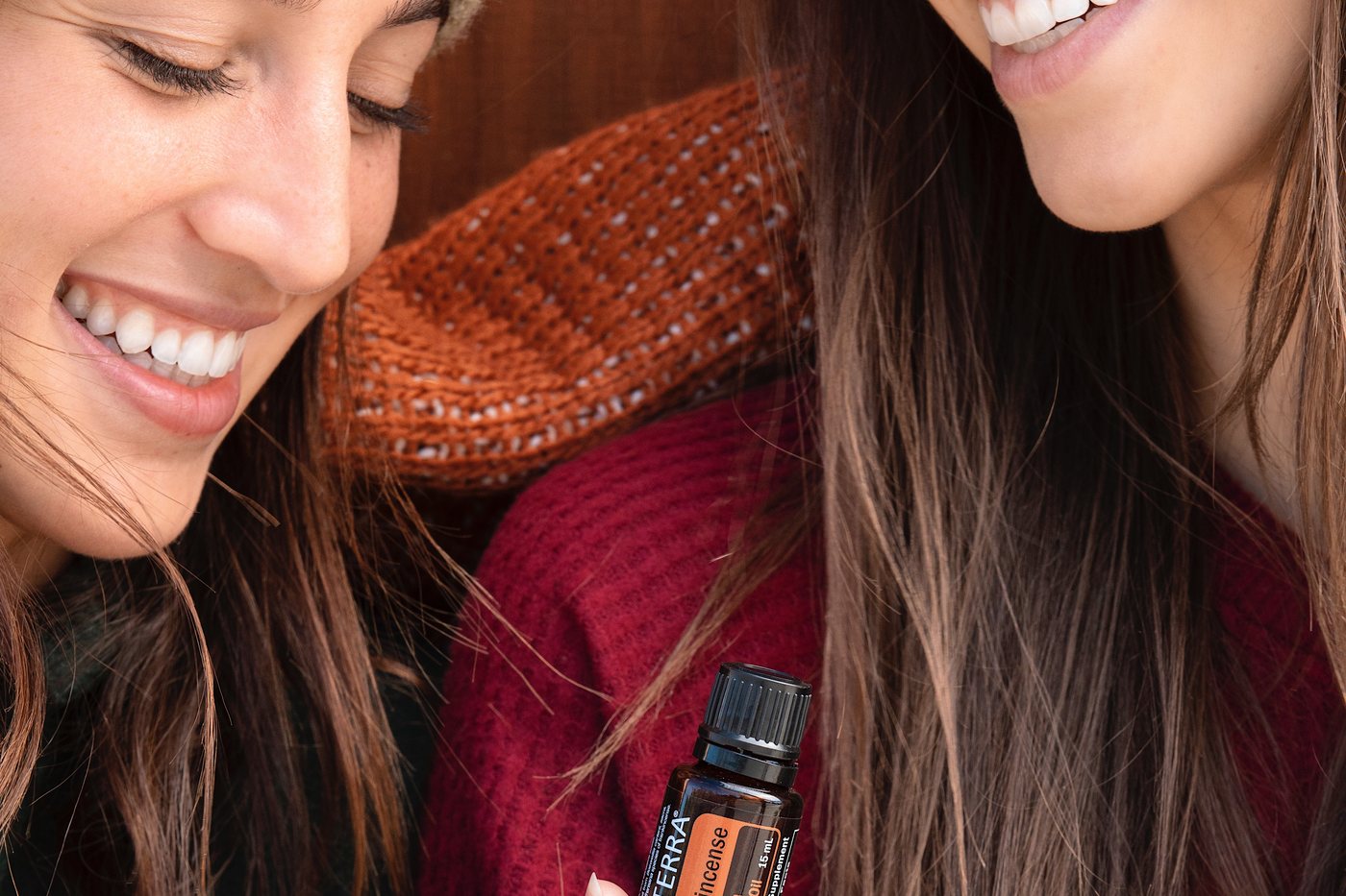 Two friends smiling and holding a dōTERRA bottle