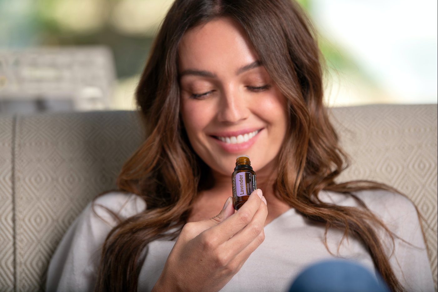A woman smelling a dōTERRA oil bottle
