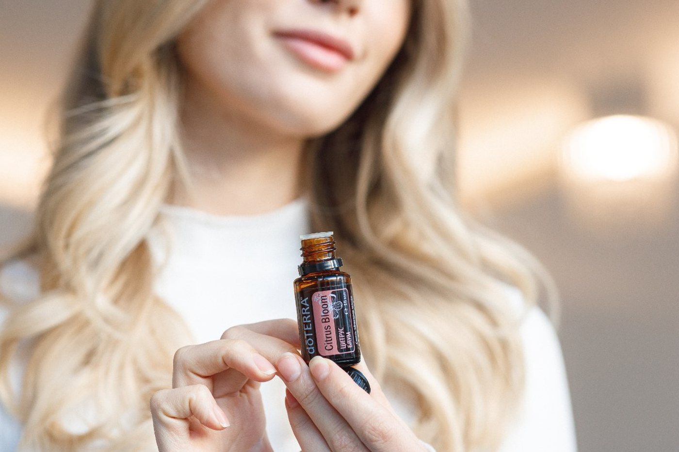 Девушка держит флакон dōTERRA и рассматривает этикетку